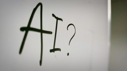 The letters AI and a question mark written in marker on a whiteboard