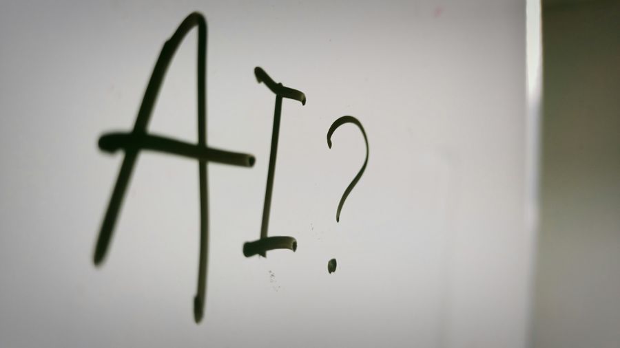 Las letras IA y un interrogante escritos con rotulador en una pizarra blanca