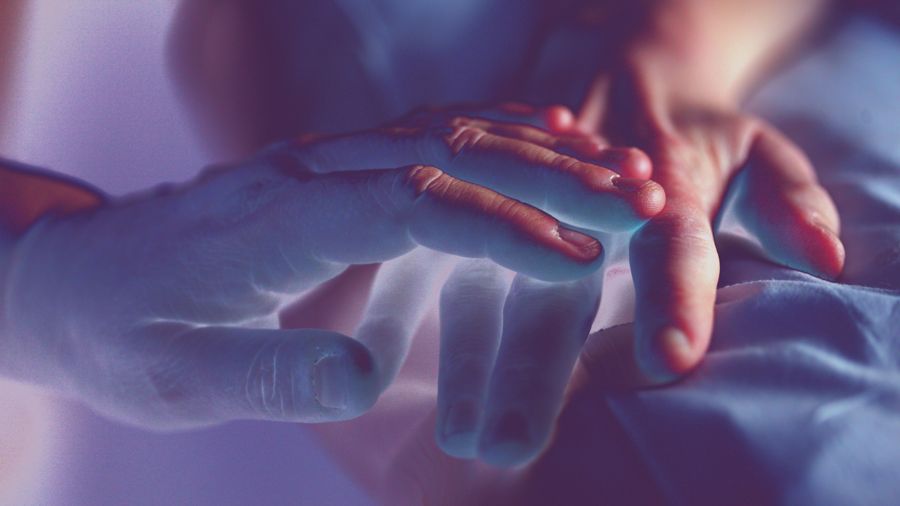 Una mano descansando sobre otra en penumbra azulada