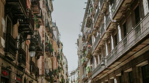 Una calle estrecha de Barcelona, con edificios de viviendas antiguos y balcones de hierro