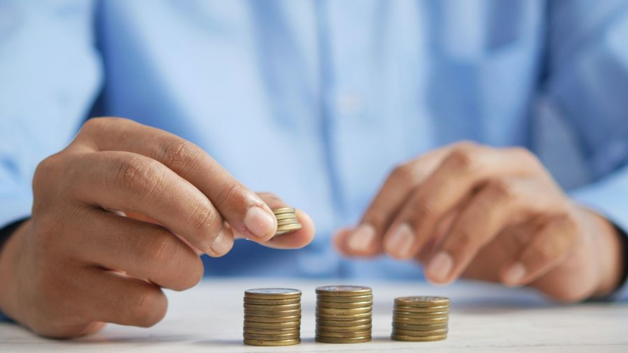 una persona apilando monedas encima de una mesa