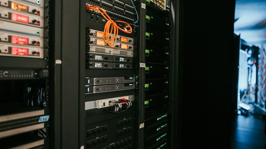 Server racks with green status lights, a coiled orange cable and labels stuck on by hand