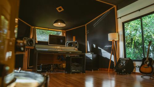 Un estudio de grabación vacío, con la mesa de mezclas y una guitarra en su soporte, sin nadie tocando